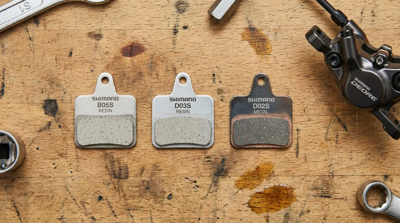 Drei Shimano Bremsbeläge B05S, D03S und D02S nebeneinander auf Werkbank - Trekking-Bremsbelag-Vergleich